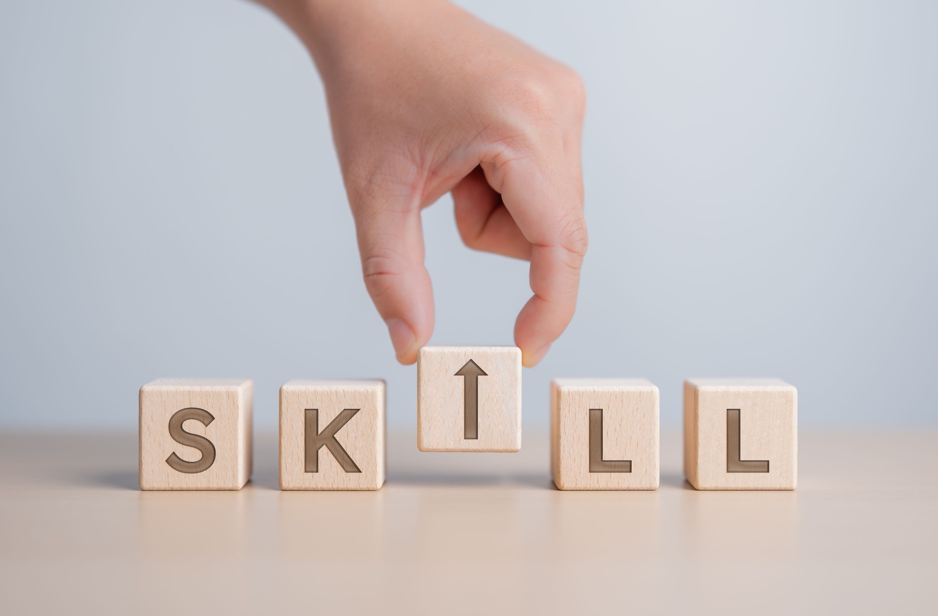 Hand select the arrow up icon with SKILL words on wooden cubes. Upskilling and personal development concept. Upskill training, knowledge and education, learning, ability. Up-skilling, Re-skilling.